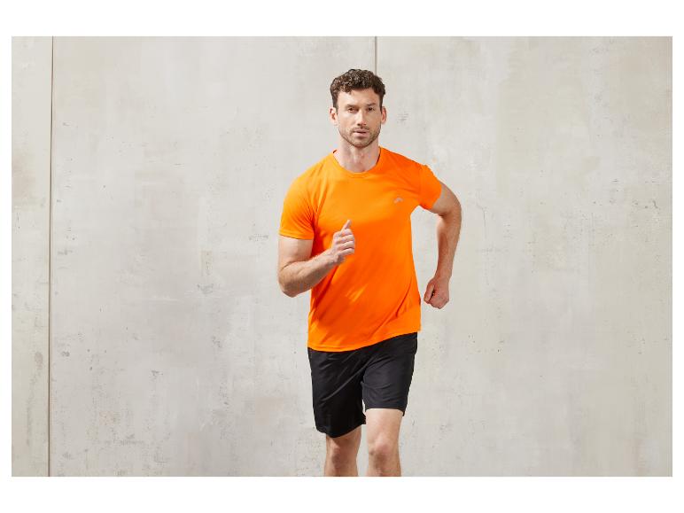 Homme en T-shirt orange et short noir courant face à un mur en béton.
