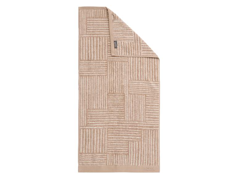 Serviette de bain beige avec motif géométrique à rayures et bordure unie.
