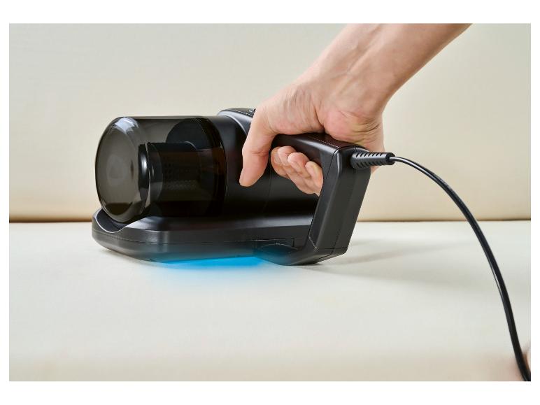 Aspirateur à main avec lumière bleue sur une surface claire, tenu par une main.