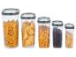 Cinq récipients transparents avec pâtes, maïs, café et avoine.