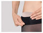 Une femme enfile des collants noirs avec une ceinture beige.