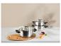 Casseroles en acier inoxydable avec couvercles en verre, avec carottes et oignon sur une table.