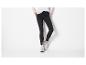 Femme en pantalon noir moulant et baskets blanches et grises.