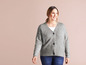 Une femme portant un cardigan gris à boutons et un jean bleu.