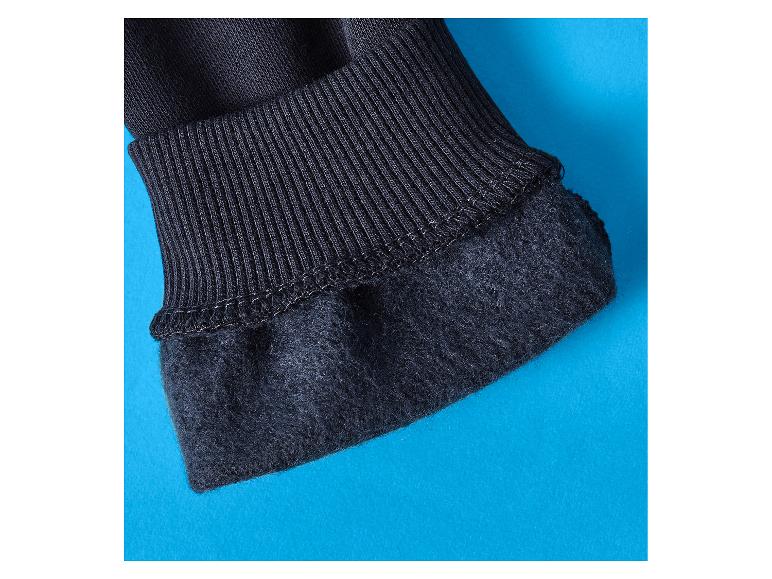 Gros plan d'un poignet côtelé noir et d'un tissu doublé sur fond bleu.