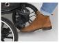 Pied en botte marron et jean, appuyant sur le frein d'une poussette.