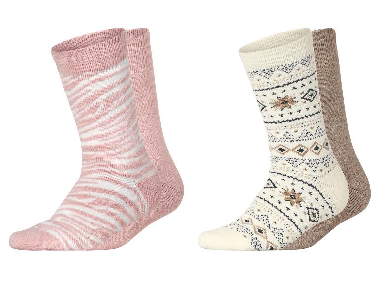 Deux paires de chaussettes, une rose à rayures blanches, l'autre crème à motif nordique.