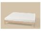 Cadre de lit en bois clair avec matelas blanc sur fond beige.