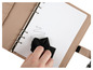 Un agenda en cuir beige avec un chiffon noir pour nettoyer une page.