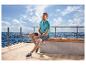 Homme en polo bleu et short, portant des chaussures de loisirs ESMARA MEN, assis au bord de la mer.