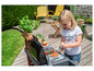 Un enfant joue avec un set de barbecue jouet Smoby sur une terrasse en bois.