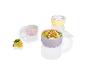 Un bol rose et jaune à pois blancs, avec un couvercle et rempli de fruits.