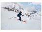 Enfant en tenue de ski bleue et casque noir skiant sur une pente de montagne enneigée.