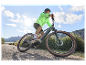Un homme roule à vélo électrique Maxxis sur une route ensoleillée.