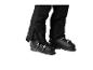 Pantalon de ski noir et chaussures de ski sur fond blanc.