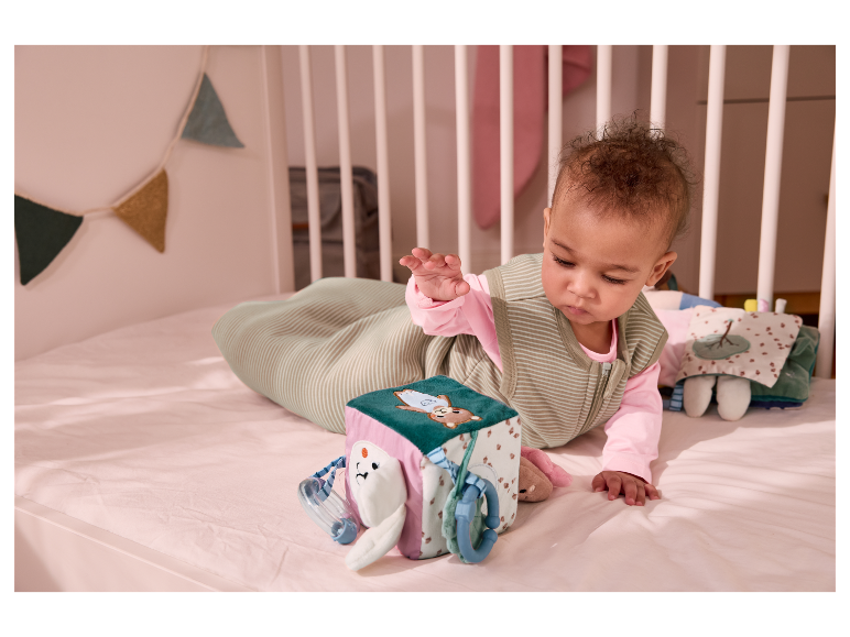 Un adorable bébé explore un jouet en cube doux de Baby Clementoni.