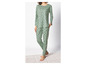 Une femme porte un pyjama vert avec des cœurs blancs.