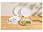 Assiettes blanches avec salade fraîche et couverts sur une table en bois.