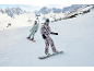 Deux snowboarders skient en montagne, vêtus de combinaisons de snowboard et de lunettes.