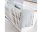 Lit bébé avec cadre en bois blanc, édredon gris et oreiller.