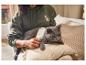 Femme brossant un chat avec une brosse blanche, le chat est gris, la femme porte un sweat à capuche vert.
