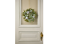 Couronne d'hiver avec feuillage vert, baies blanches et pommes de pin sur une porte.
