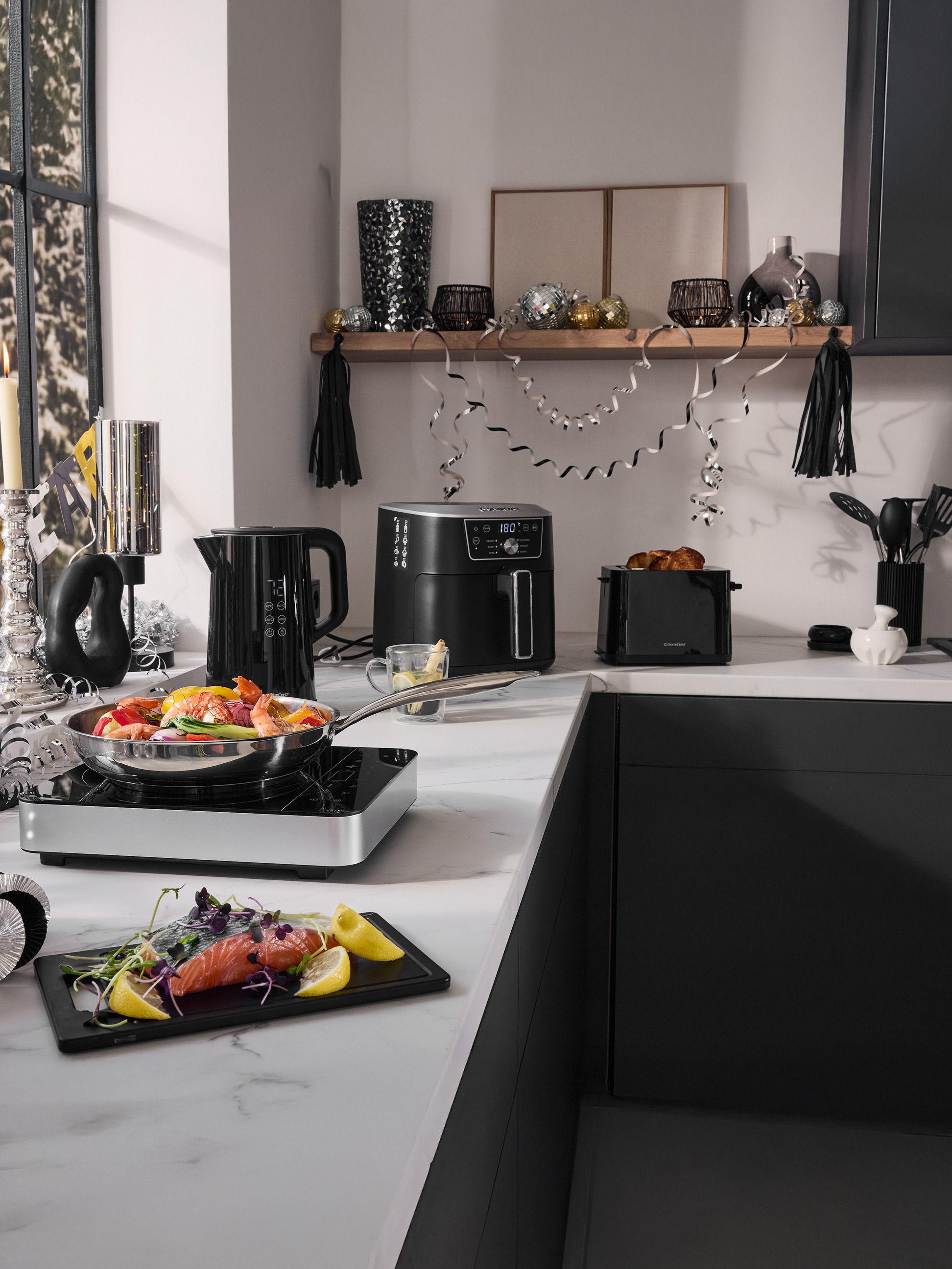 Comptoir de cuisine avec friteuse à air SilverCrest, bouilloire, grille-pain et ustensiles de cuisine, décoré pour une fête.