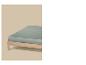 Un matelas vert clair sur un cadre de lit en bois sur fond beige.