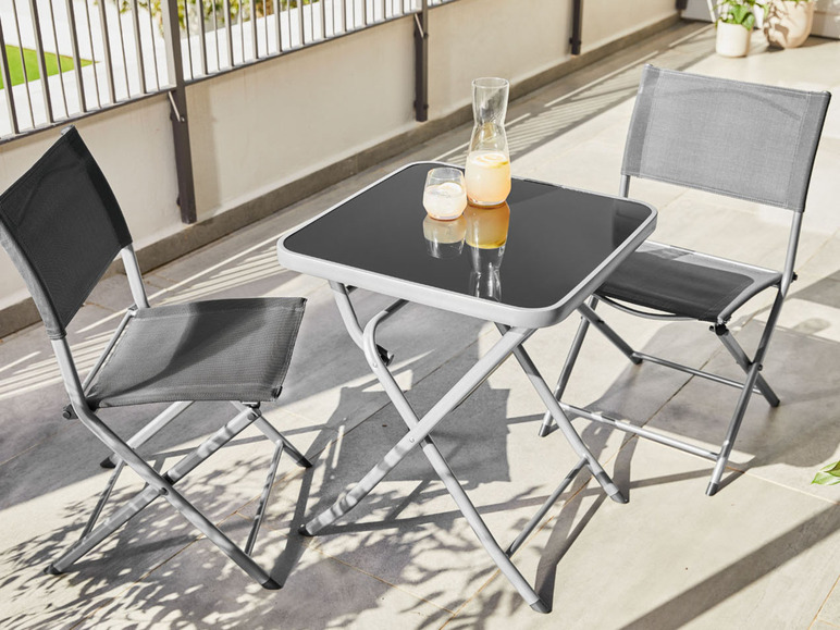 Deux chaises pliantes et une table en verre sur une terrasse.