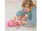Une enfant joue avec une poupée bébé sur un tapis, l'habillant d'une tenue rose.