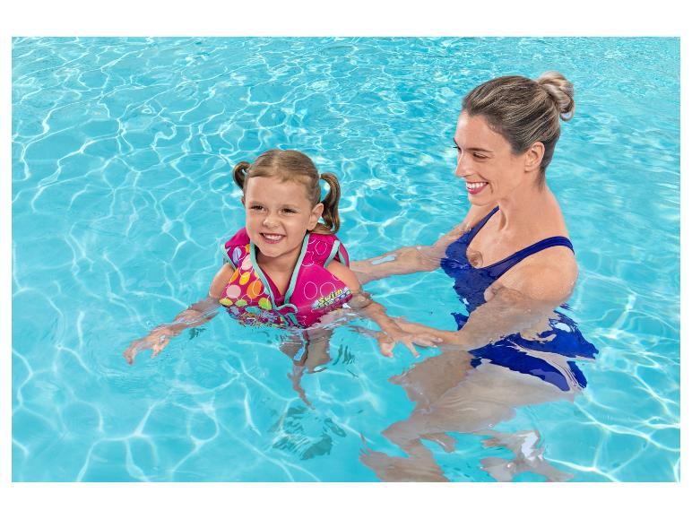 Femme et fille en gilet de natation coloré dans la piscine, souriantes.