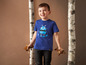 Un garçon porte un t-shirt bleu avec un motif de robot et tient des feuilles.