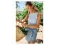 Une femme portant un haut blanc et une jupe en jean porte un panier en osier avec des légumes.