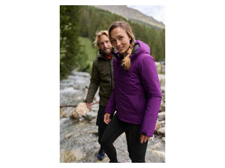 Deux randonneurs en vestes et pantalons d'hiver près d'une rivière en montagne.