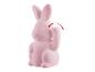 Une figurine de lapin rose avec une patte levée.