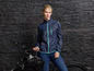 Une femme en veste bleue avec un casque de vélo et un vélo.