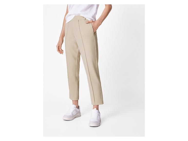 Femme en pantalon beige et baskets blanches.