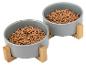 Deux gamelles grises pour animaux de compagnie avec supports en bois, remplies de croquettes.