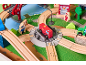 Ensemble de train en bois avec camion de pompiers rouge, rails et figurines sur un tapis de jeu.