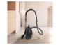 Aspirateur traîneau noir avec poignée chromée et tuyau flexible sur un tapis.