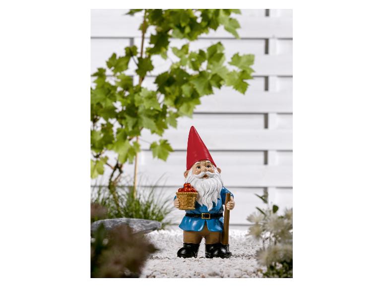 Un nain de jardin avec un panier de baies rouges
