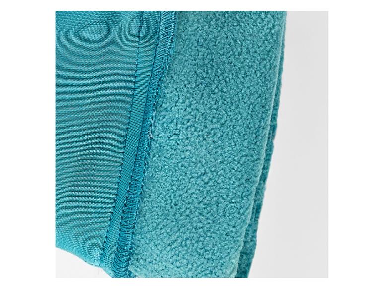 Détail d'une couture entre du tissu tricoté et du polaire turquoise.