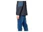 Homme portant une veste bleu foncé et sarcelle avec un jean bleu, vue de côté.
