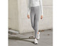 Femme portant un pull blanc et un pantalon noir avec des baskets blanches.