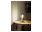 Une lampe de table dorée avec une ampoule ronde sur une petite table blanche.