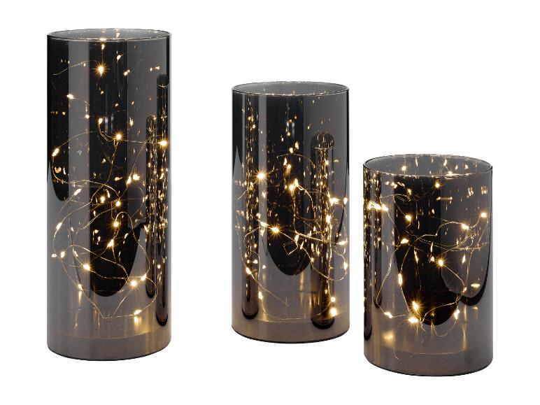 Trois lanternes cylindriques en verre avec des guirlandes lumineuses chaudes à l'intérieur, de différentes hauteurs.