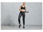 Une femme en leggings noirs et un soutien-gorge de sport tenant un ballon d'exercice.