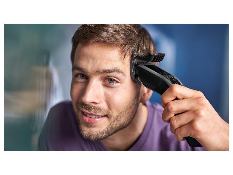 Jeune homme utilisant une tondeuse électrique pour se couper les cheveux.