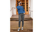 Une femme porte un pull bleu et un pantalon gris avec un appareil photo à la main.
