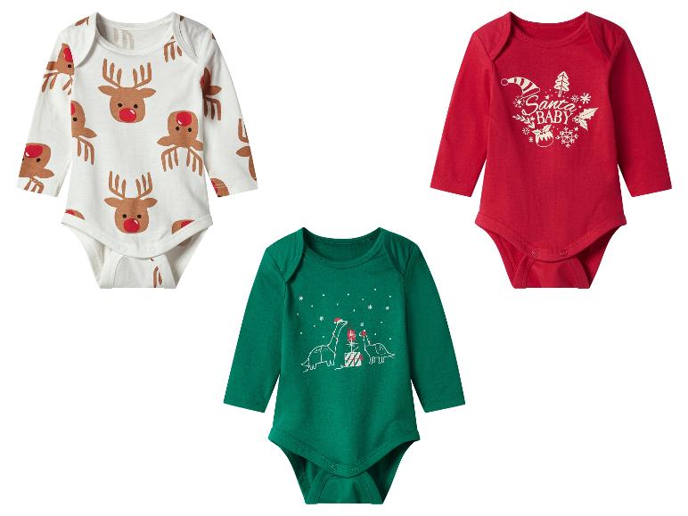 Trois bodys de bébé sur le thème de Noël : un blanc avec des rennes, un rouge avec « Santa Baby » et un vert avec des dinosaures.